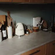 Cream retro-style kettle on a grey stone worktop beside a glass storage jar, a wine bottle and a black mixer tap