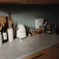 Cream retro-style kettle on a grey stone worktop beside a glass storage jar, a wine bottle and a black mixer tap