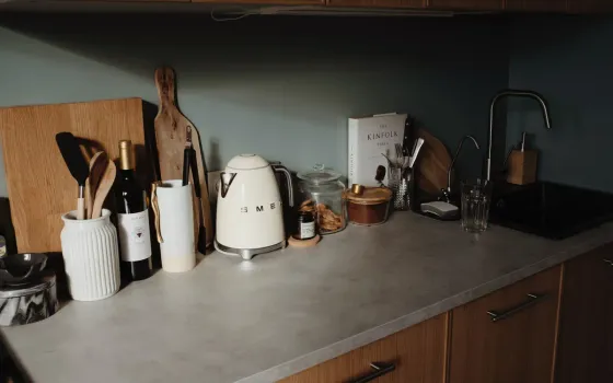 Cream retro-style kettle on a grey stone worktop beside a glass storage jar, a wine bottle and a black mixer tap