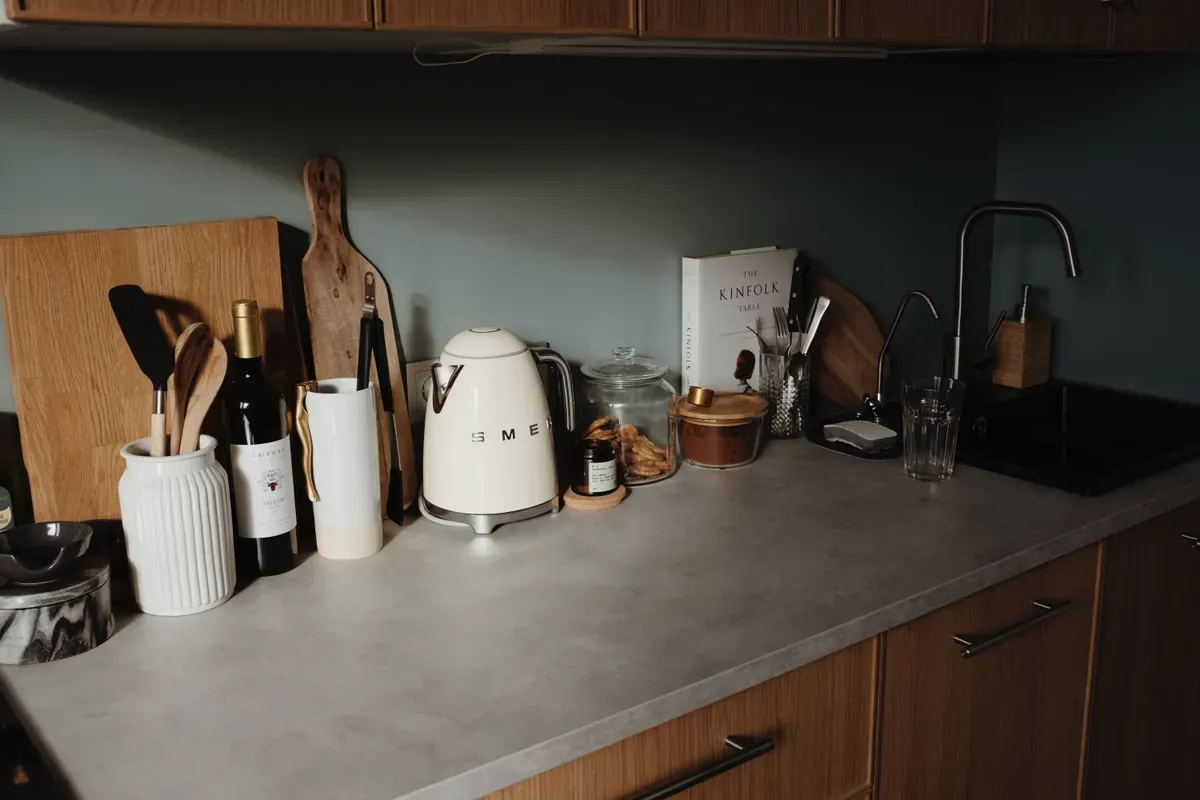 Cream retro-style kettle on a grey stone worktop beside a glass storage jar, a wine bottle and a black mixer tap
