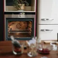 Open empty electric oven showing its fan and two wire shelves, beside a cream retro fridge freezer