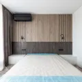 Bare double mattress with a blue-edged quilted top in a bedroom with slatted oak wall panelling and two black reading lights