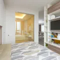 Double bed with grey chevron duvet beside an open shelving unit holding a television and books