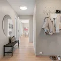 Grey-painted hallway with two coats on a white peg rail, a round mirror and a black bench