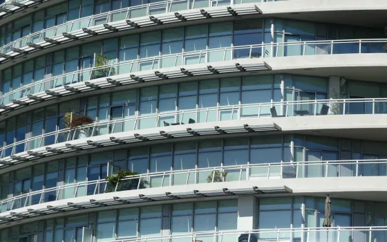 Curved modern apartment block with tiers of glass balconies, metal railings and outdoor chairs stacked in rows