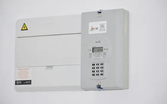 Digital prepayment electricity meter and consumer unit mounted on a plain white wall