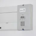 Digital prepayment electricity meter and consumer unit mounted on a plain white wall