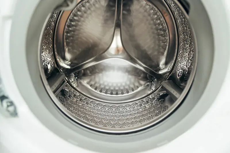 Empty stainless steel drum of a front-loading washing machine seen through the open door